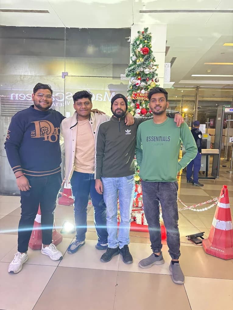 Four colleagues in sweatshirts and a cream jacket, arms round each other's shoulders, in front of the decorated Christmas tree in the building lobby.