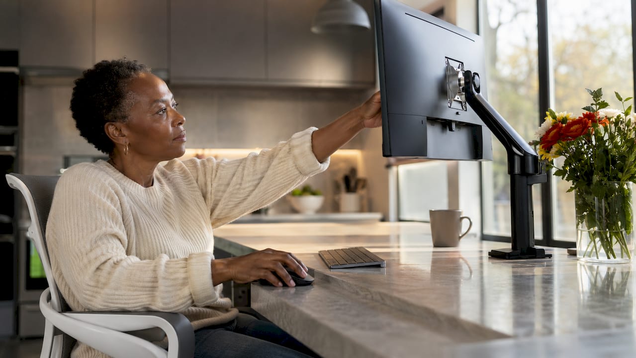 Woman adjusting monitor in ergonomic home office